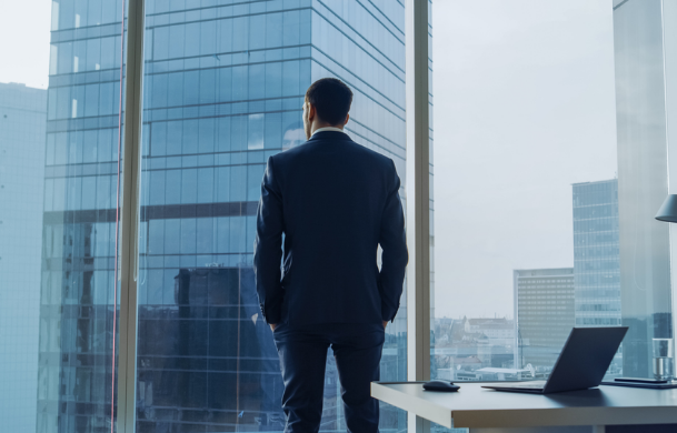 Executive looking out office window onto the city below.